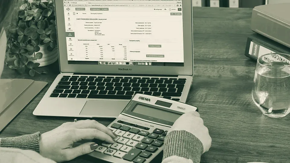 Persona trabajando con calculadora y planilla contable en la computadora